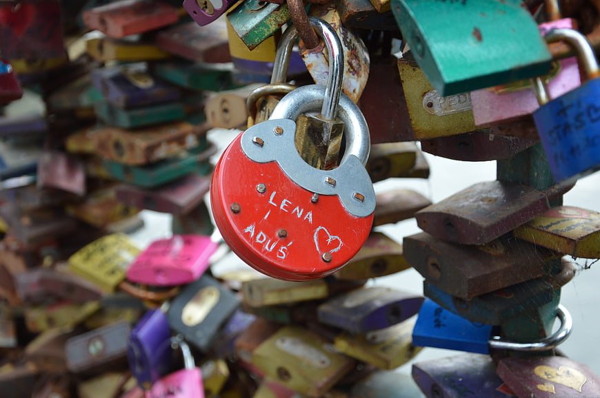 Red heart-shaped love padlock with names engraved on bridge