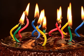 Close-up of chocolate birthday cake with colorful lit candles