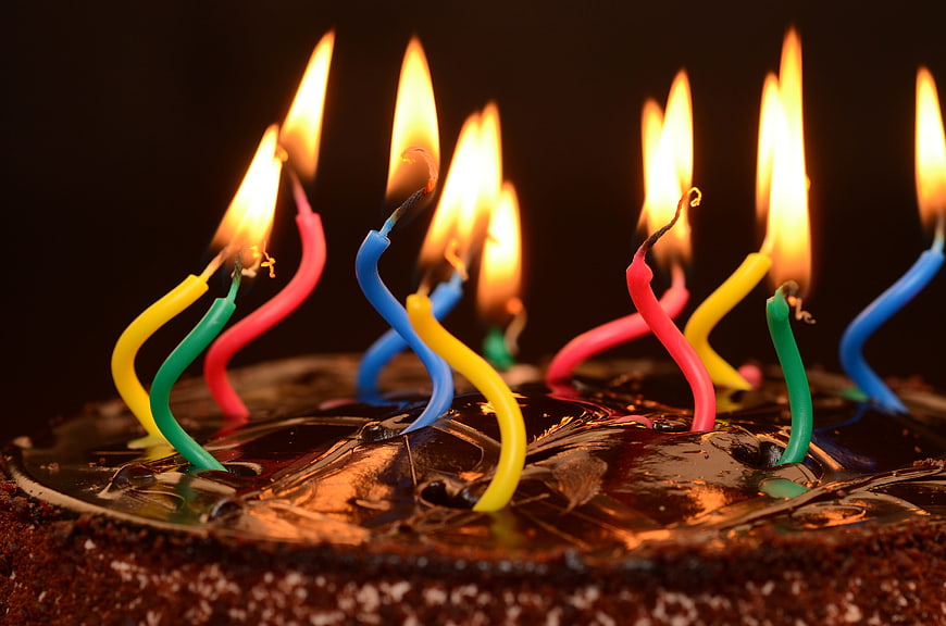 Close-up of chocolate birthday cake with colorful lit candles