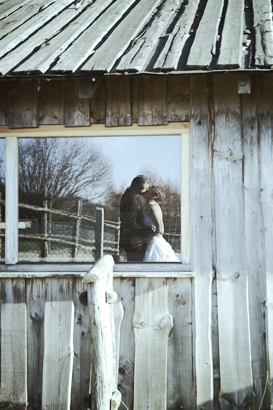 Wedding couple reflection in rustic wooden barn window