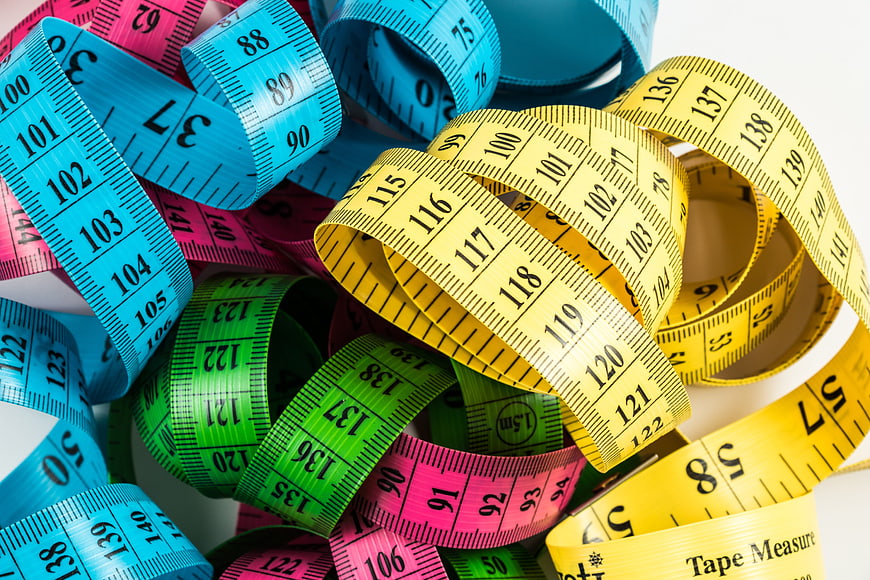 Colorful measuring tapes coiled on white background