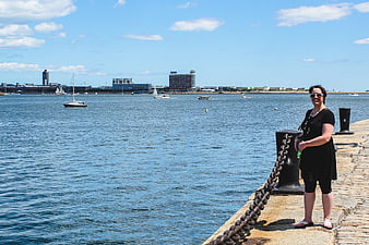 Woman standing on harbor pier with city skyline background