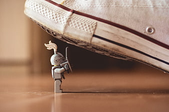 Lego knight toy standing under a large sneaker shoe