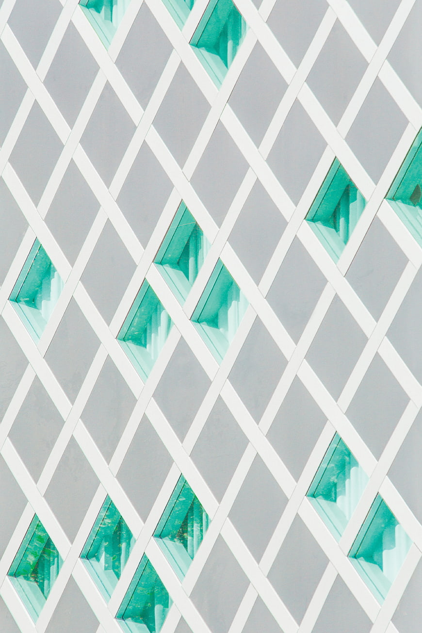 Modern building facade with geometric diamond pattern and teal windows