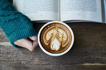 Overhead view of latte art coffee cup with open book