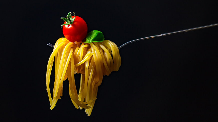 Spaghetti with Cherry Tomato on Fork Against Black Background