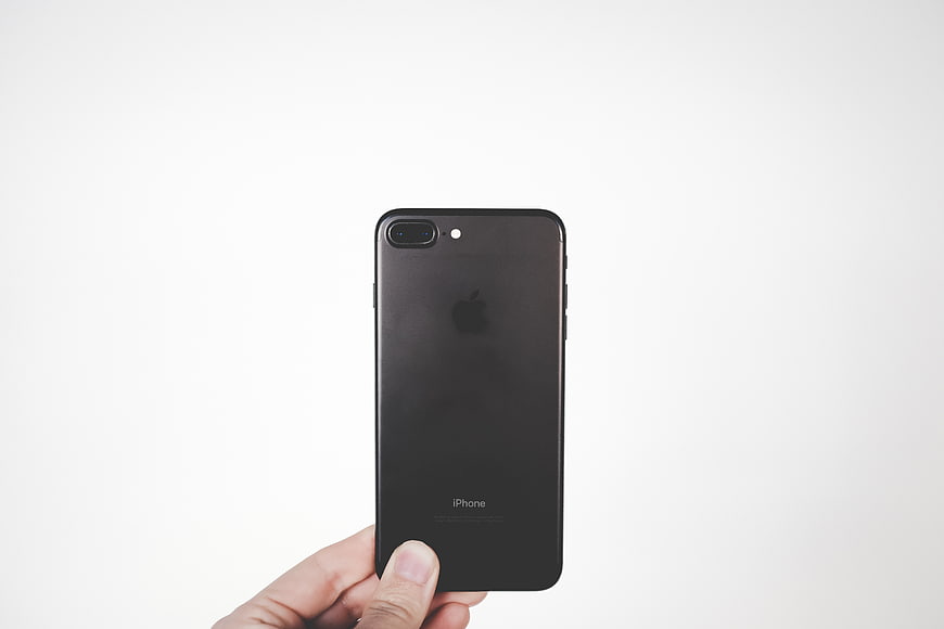 Hand holding black iPhone against white background