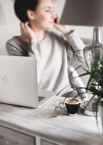 Woman on phone with laptop and coffee at desk