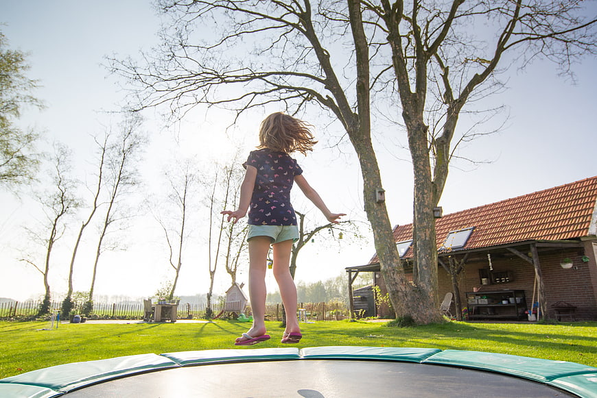 Young Girl Jumping On Trampoline In Backyard