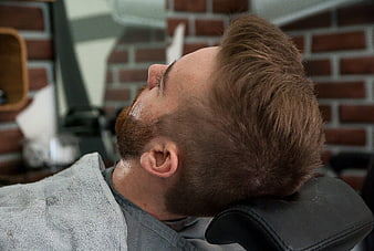Man with fresh haircut and beard in barber chair