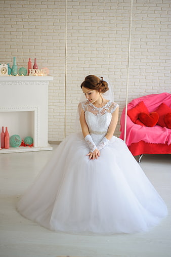 Young Bride in White Gown Seated on Swing with Red Sofa