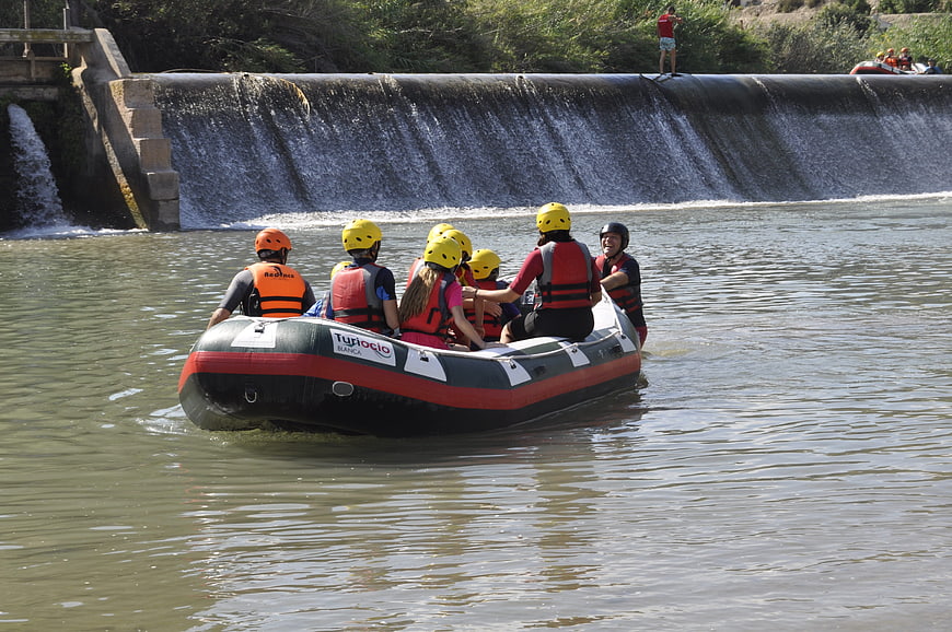 Group of people rafting on a river near a dam