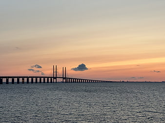 Silhouette of cable-stayed bridge over ocean at sunset