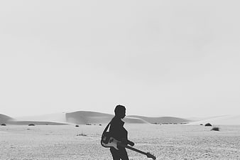Silhouette of woman with electric guitar in desert landscape