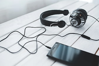 Black vintage headphones and smartphone on white wooden table