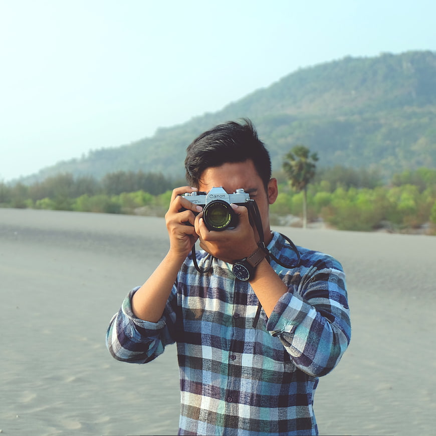 Man Taking Photo with Vintage Camera on Beach