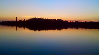 Serene Lake Sunset with Tree Silhouette and Sky Reflection