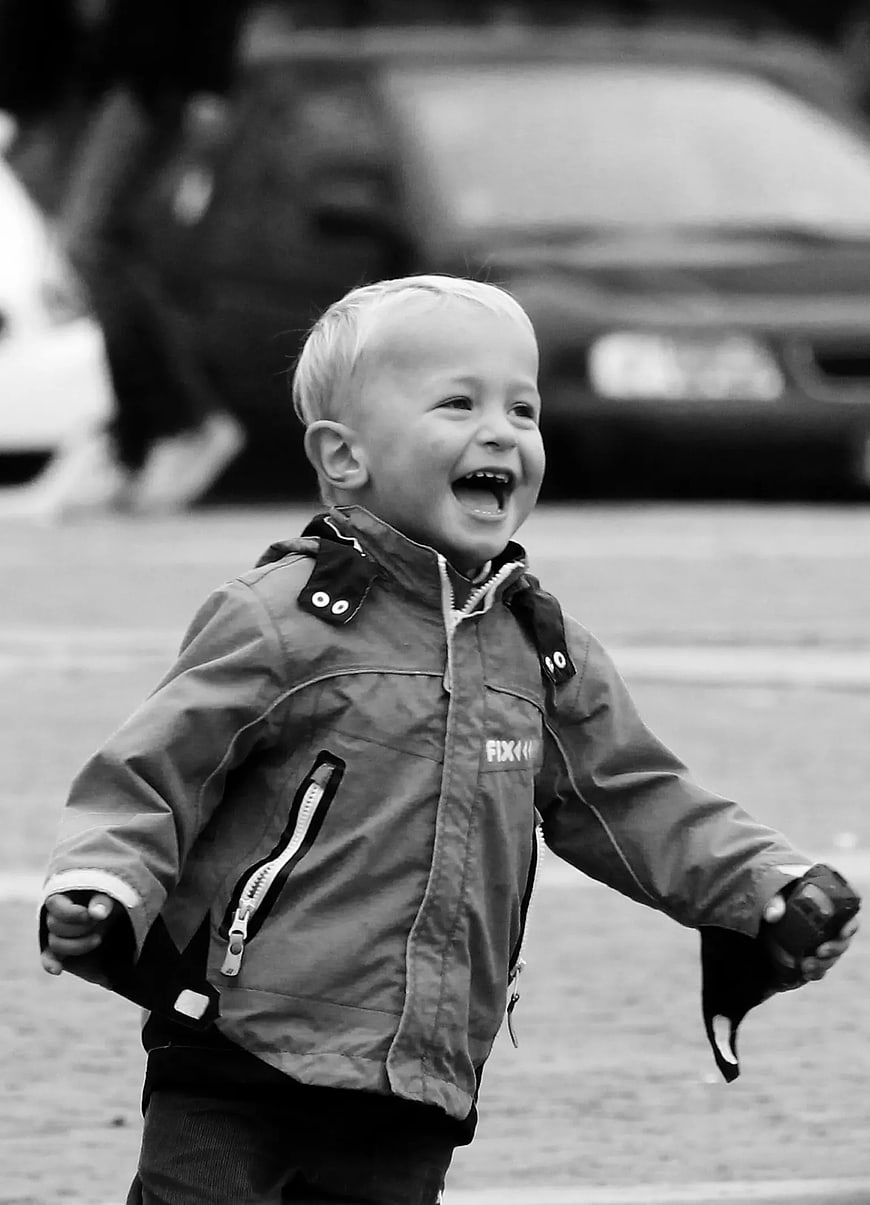 Laughing Toddler Boy in Jacket on Street