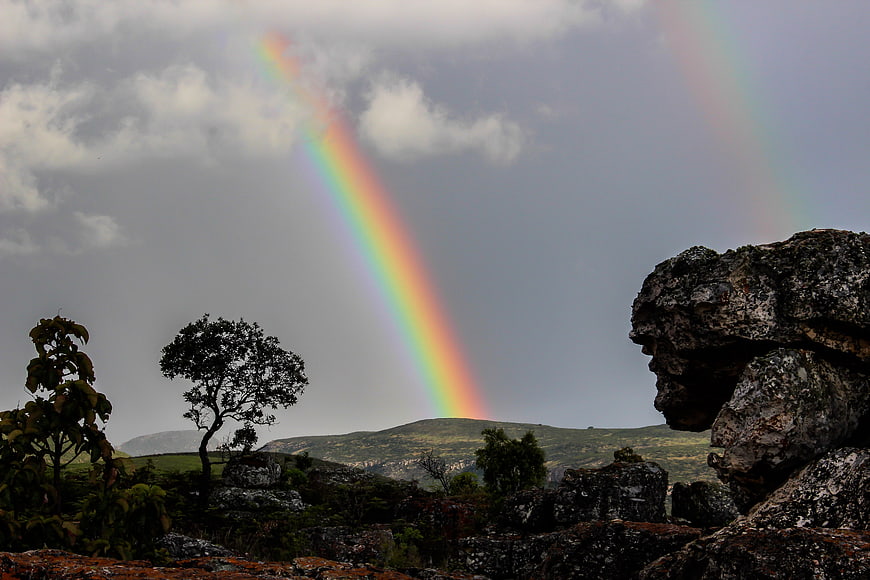 Vibrant Rainbow Over Rocky African Landscape with Trees