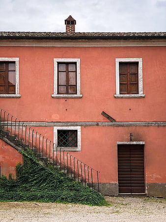 Weathered Pink Building Facade with Stairs and Ivy