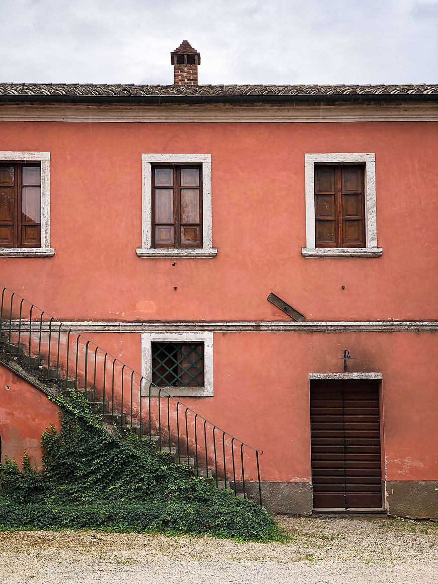 Weathered Pink Building Facade with Stairs and Ivy