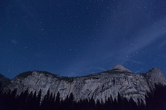 Starry Night Sky Over Granite Mountain Cliffs and Pine Forest
