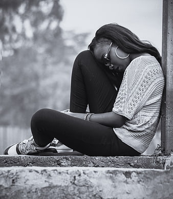 Sad woman sitting alone on concrete ledge in black and white
