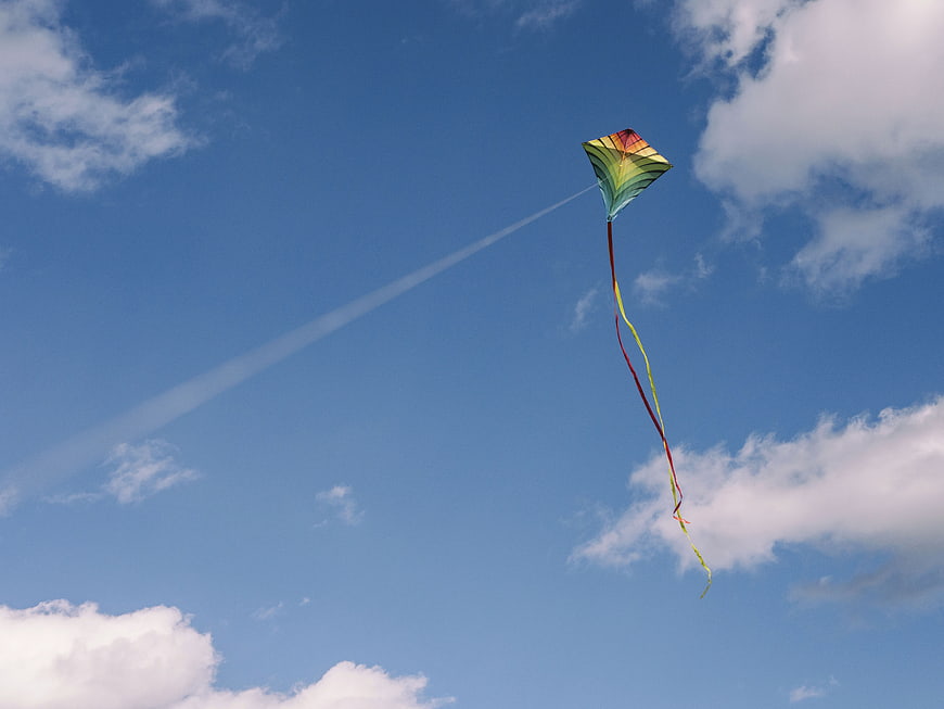 Colorful Rainbow Kite Flying in Blue Sky with Clouds