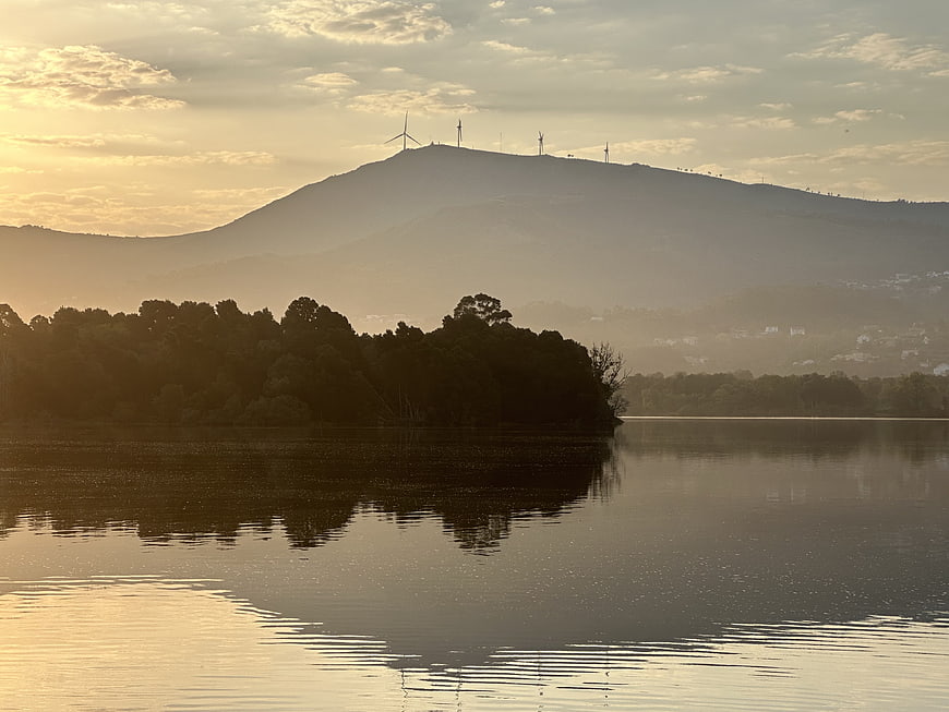 Serene Lake Landscape with Wind Turbines on Distant Mountain at Sunset