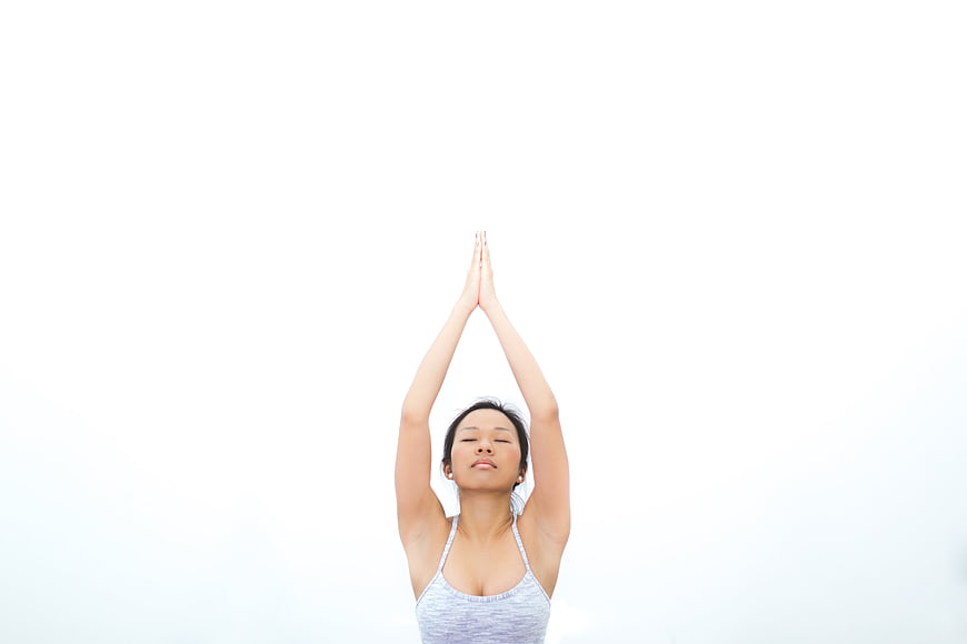 Woman performing yoga stretch with hands clasped overhead