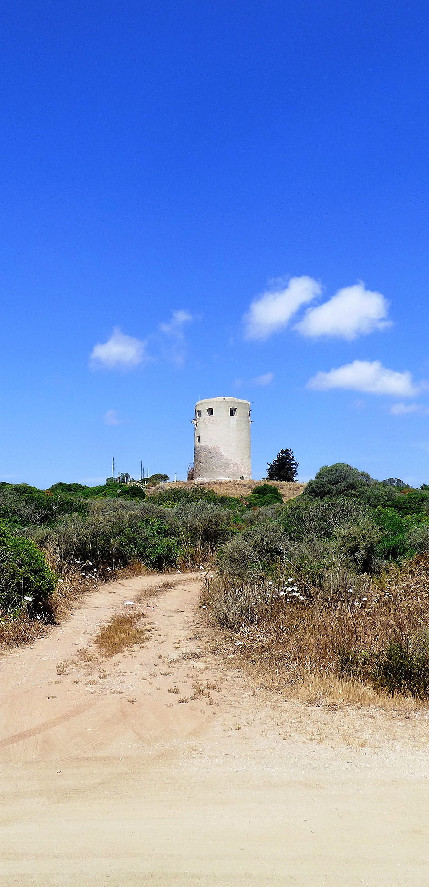 Dirt path leading to historic watchtower in Sardinia