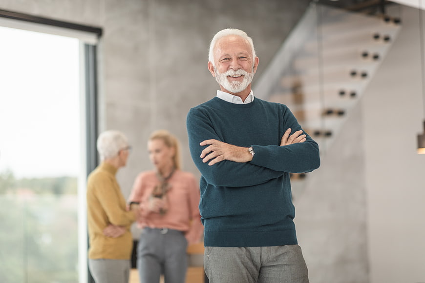 Confident Senior Man in Modern Office with Colleagues