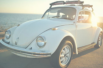 Classic White Volkswagen Beetle with Surfboard at Sunset