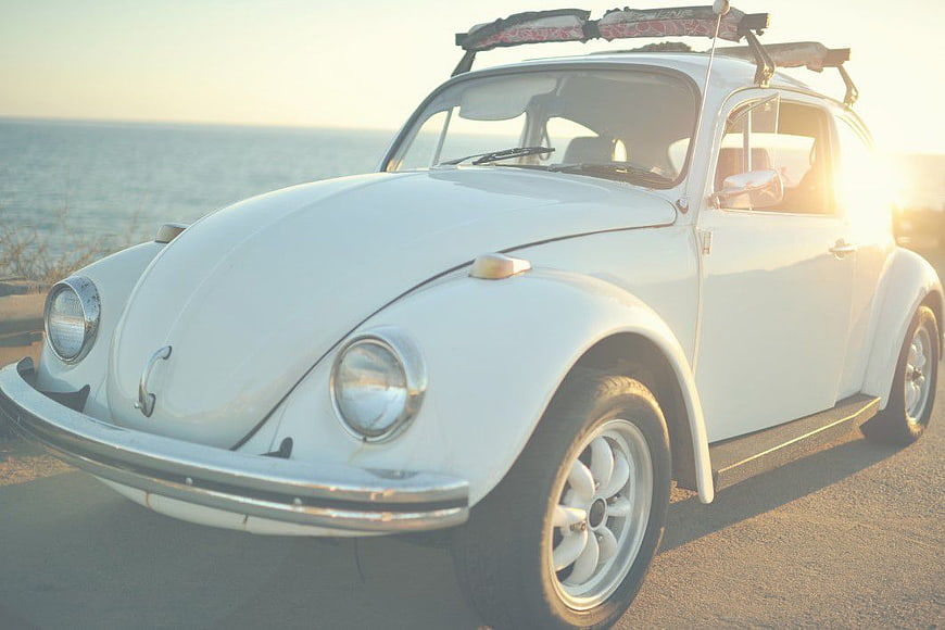 Classic White Volkswagen Beetle with Surfboard at Sunset