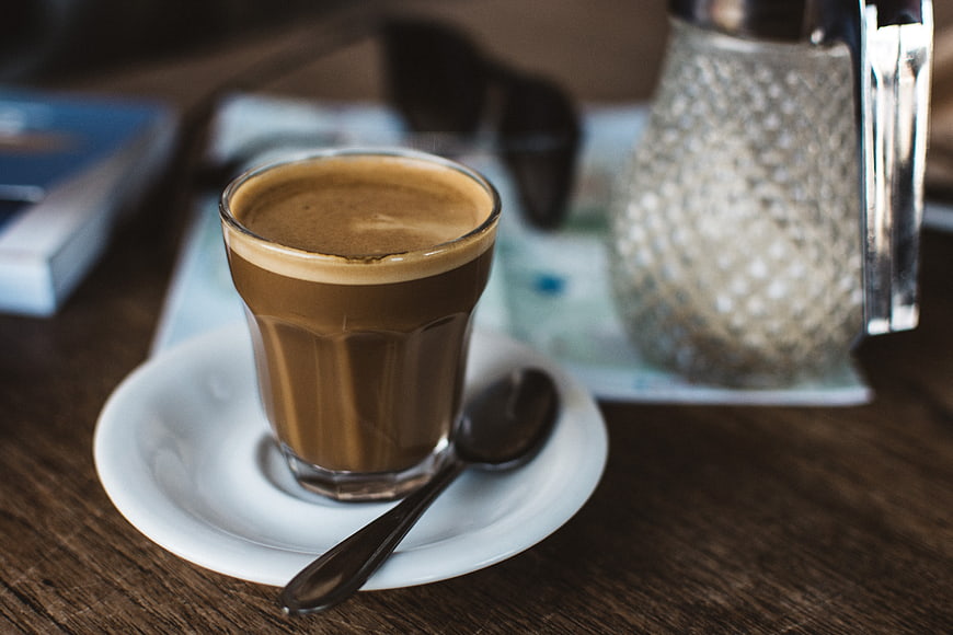 Close-up of a cortado coffee in a glass cup on a wooden table