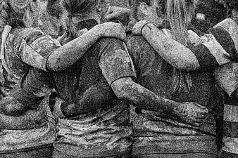 Muddy female athletes hugging in a tight team huddle