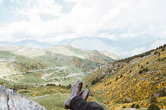 Hiker boots overlooking winding mountain road in autumn