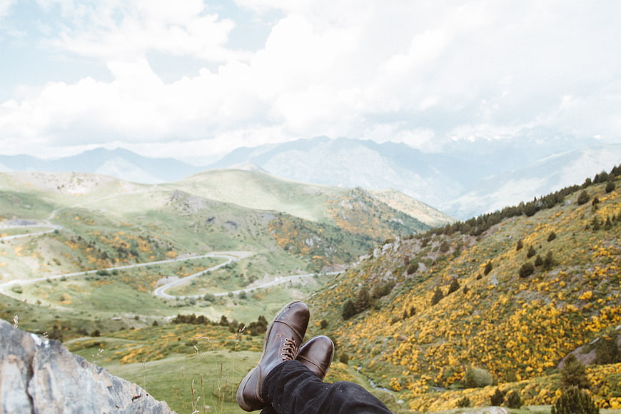 Hiker boots overlooking winding mountain road in autumn