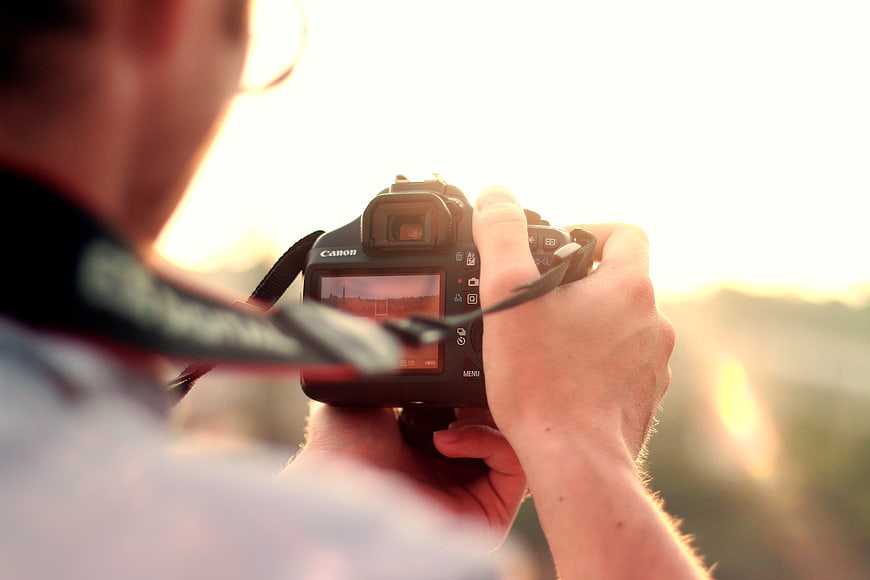 Photographer holding DSLR camera at sunset