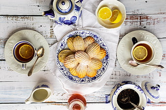 Top view of madeleine cookies with tea and lemon on rustic table