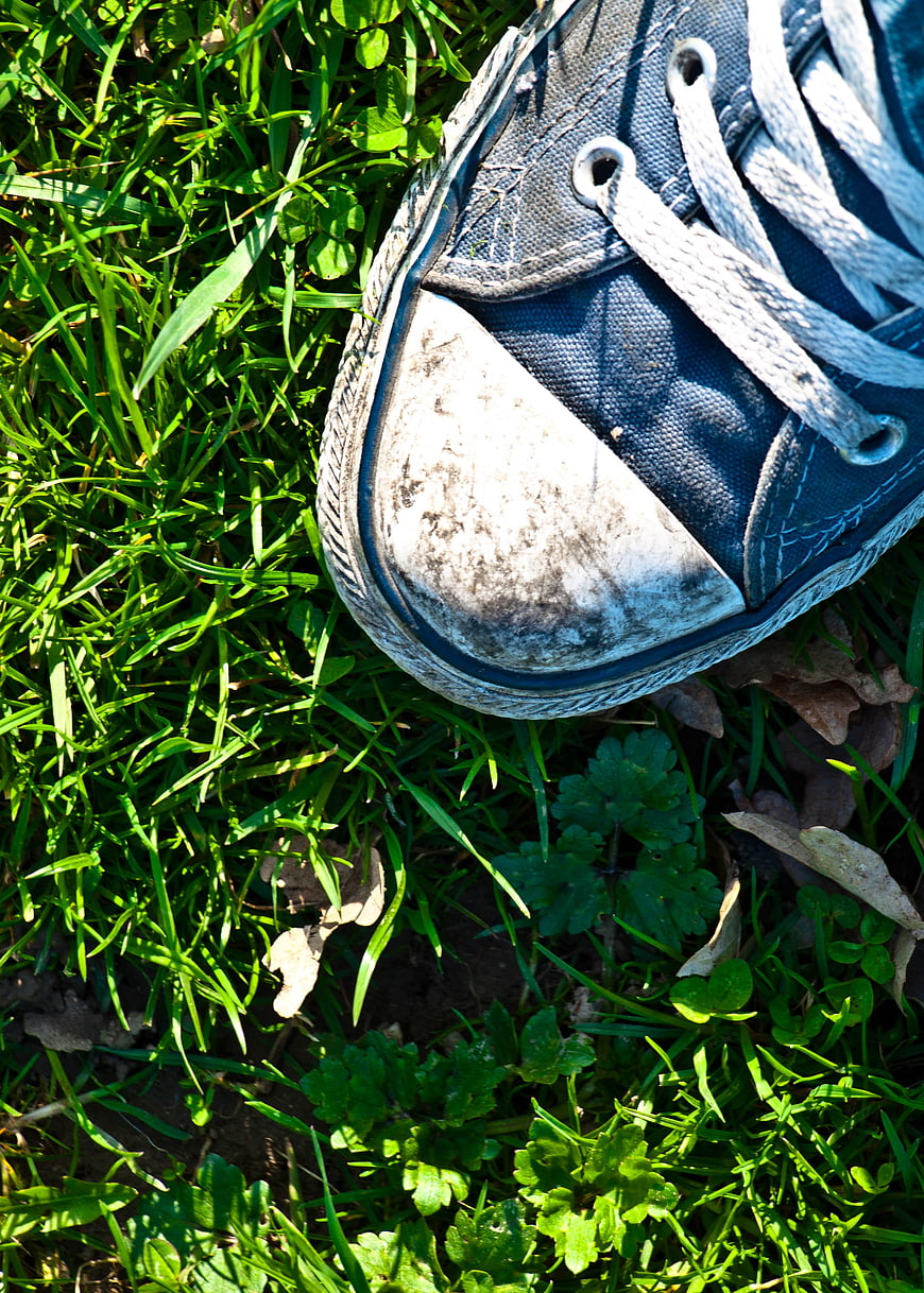Close-up of worn blue canvas sneaker on green grass