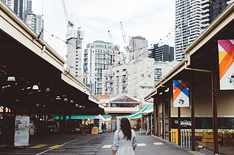 Woman Walking Away in Urban Market with City Skyline