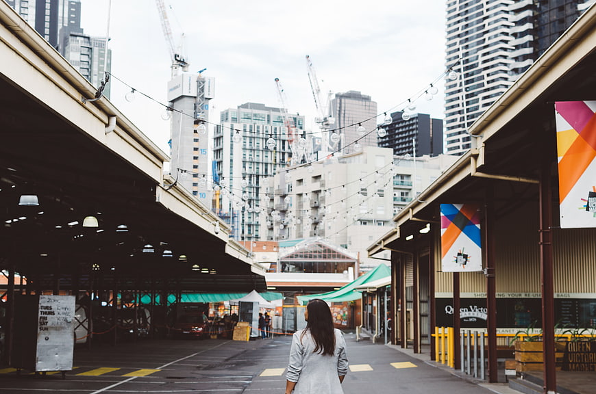 Woman Walking Away in Urban Market with City Skyline