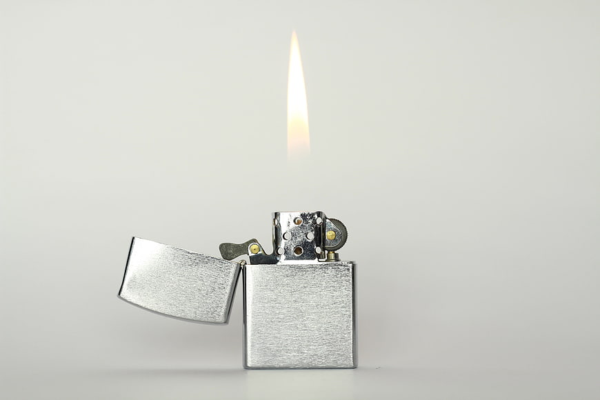 Silver lighter with flame on white background