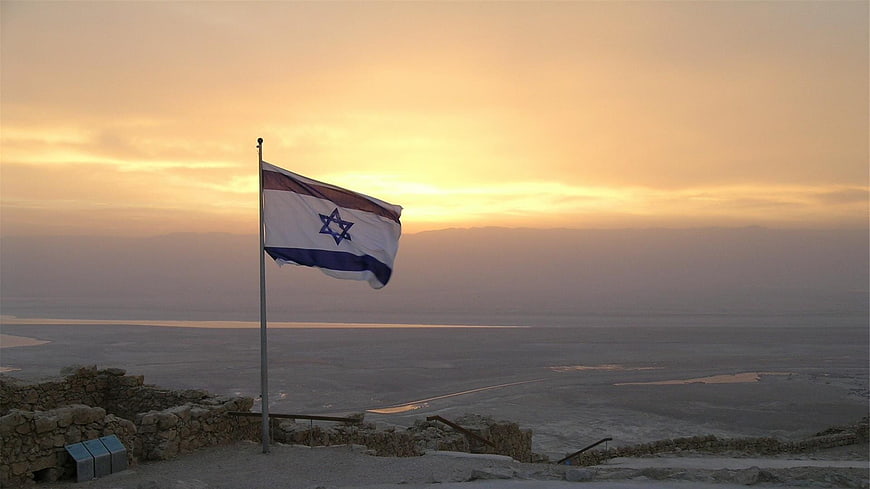 Israeli flag waving at sunset over Dead Sea landscape