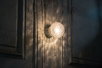 Vintage Sconce Light Casting Intricate Patterns on Weathered Wooden Door