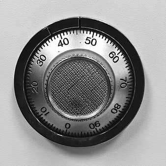 Close-up of a circular metal combination lock dial on a white background