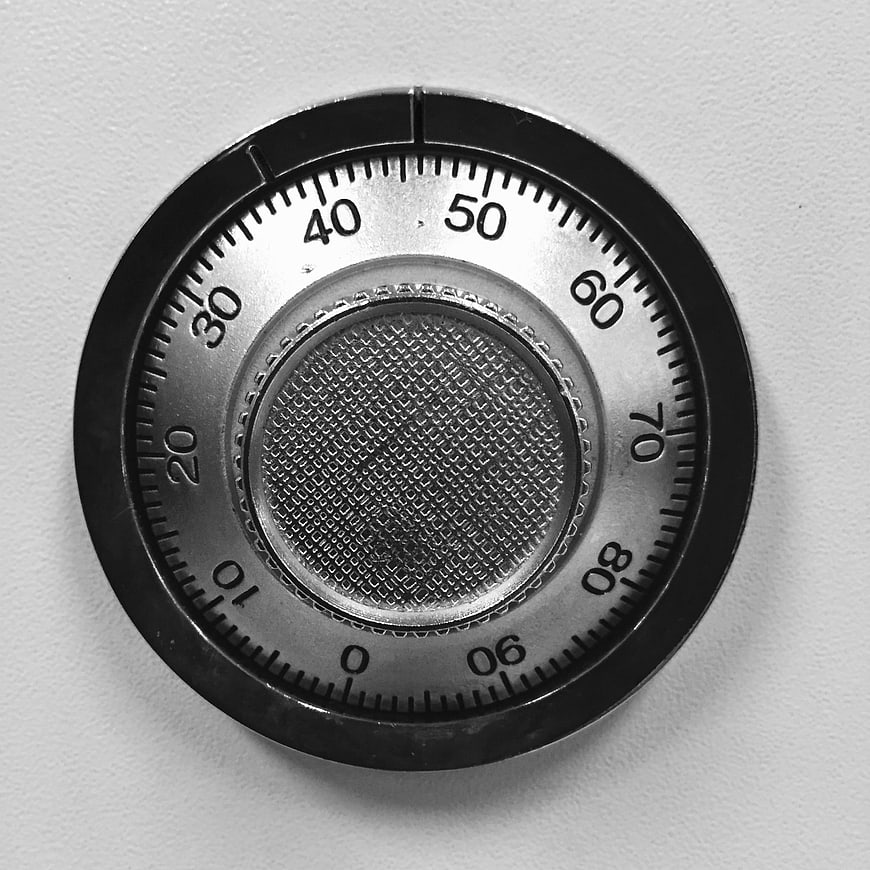 Close-up of a circular metal combination lock dial on a white background