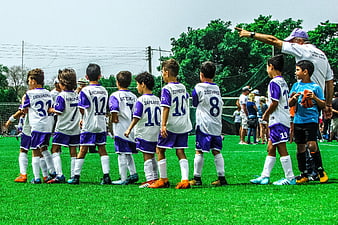 Youth Soccer Team Huddle With Coach On Green Field