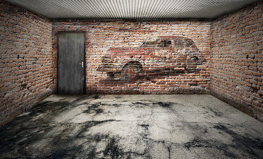 Abandoned Brick Garage Interior With Faded Car Graffiti And Concrete Floor